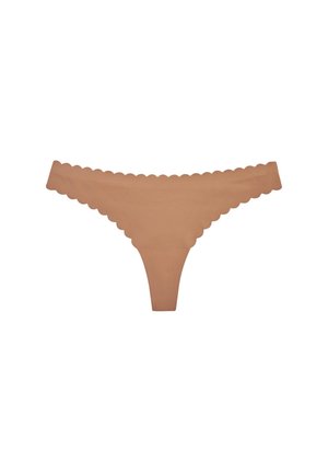 Tanga sin costuras de color nude con bordes festoneados, diseñado para un ajuste suave e invisible bajo la ropa.