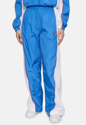 Pantalones deportivos azules y blancos con acentos rojos, hechos de nylon brillante, con una cintura elástica y un parche de logo en el lado izquierdo.