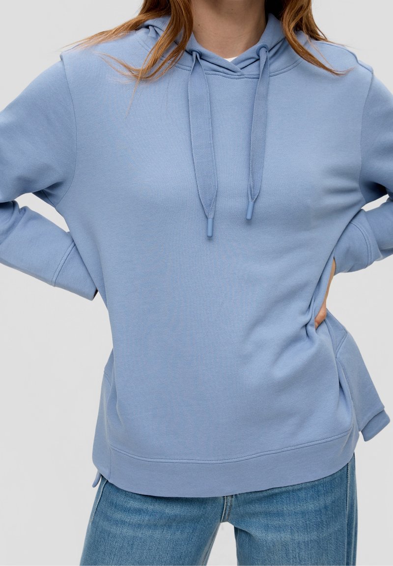 Sudadera azul claro con capucha ajustable, puños acanalados y aberturas laterales. Hecha de material suave, presenta un ajuste holgado y un diseño casual.