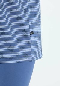 Top a rayas azul con estampados florales, mangas cortas y una etiqueta en el lateral. Combinado con leggings azul sólido.