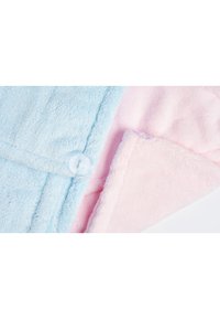 Lys blå og myk rosa fleece stoff som overlapper, med en knappdetalj på den blå siden og en glatt tekstur på begge sider.
