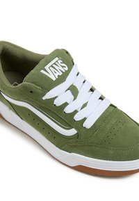 Groene suède sneaker met witte veters en logo, voorzien van perforaties en een witte rubberen zool met een bruine zooldetail.