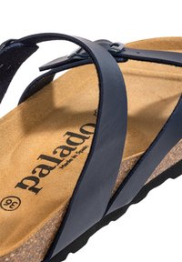 Navy leather sandal with cork footbed, featuring adjustable strap and textured outsole. The interior has a logo printed on a tan surface.
