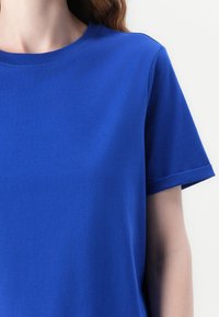 Niebieska bawełniana koszulka z okrągłym dekoltem, krótkimi rękawami i gładką teksturą. Brak wzorów lub ozdób. Prosty design.