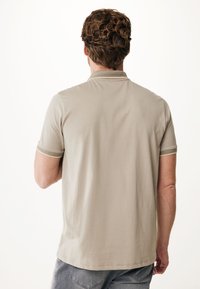 Beige kortærmet polo skjorte med tekstureret stof, der har grønne accentstriber på kraven og ærmerne. Casual pasform.