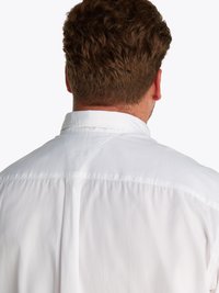Camisa blanca con un cuello clásico y diseño de canesú en la parte posterior. Confeccionada en una tela suave con una textura ligera y un sutil brillo.