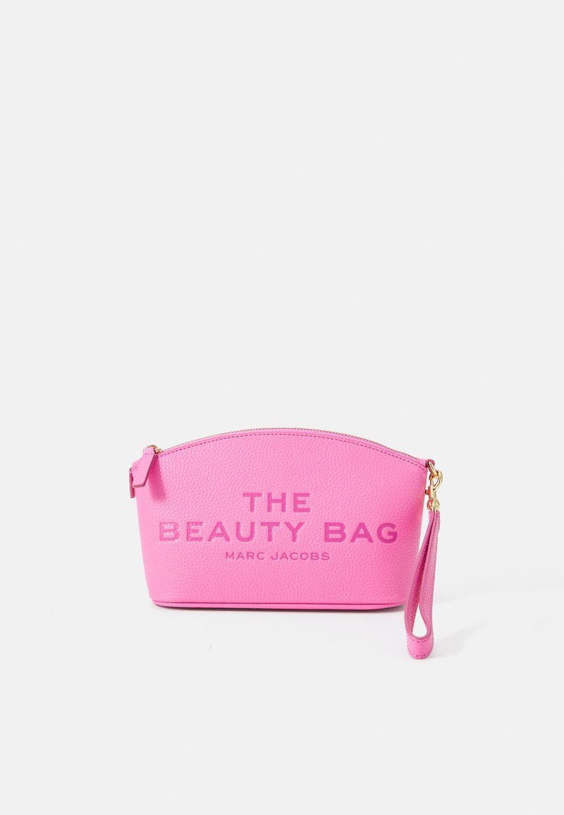 Gentă din piele roz, cu un vârf rotunjit, cu text embosat "THE BEAUTY BAG" și "MARC JACOBS", are o fermoar aurie și un breloc pentru încheietură.