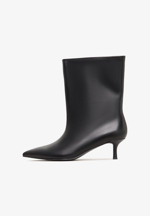 Botte de cheville en cuir noir avec une finition lisse, un bout pointu et un petit talon. Design simple sans embellissements supplémentaires.