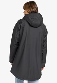 Zwarte hoodie met een gladde, matte afwerking, met een ontspannen pasvorm en een iets verlengde achterkant. Getextureerde stofdetail bij de manchetten.