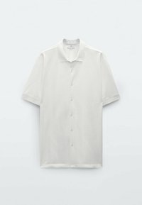 Weißes Poloshirt mit kurzen Ärmeln aus einem glatten Stoff, mit Kragen, Frontknöpfen und lockerer Passform. Ohne Muster oder Akzente.