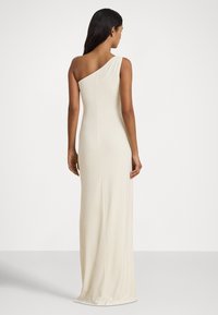 Sukienka na jedno ramię, sięgająca do podłogi, w kolorze kremowym, o dopasowanym fasonie i gładkiej, elastycznej fakturze. Prosta i elegancka sylwetka.