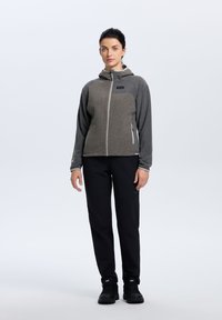 Harmaa vetoketjullinen fleece-takki hupulla, tekstuuri ylhäällä, yksivärinen alaosa, yhdistettynä mustiin housuihin ja tukevasti mustiin saappaisiin. Minimalistinen muotoilu.