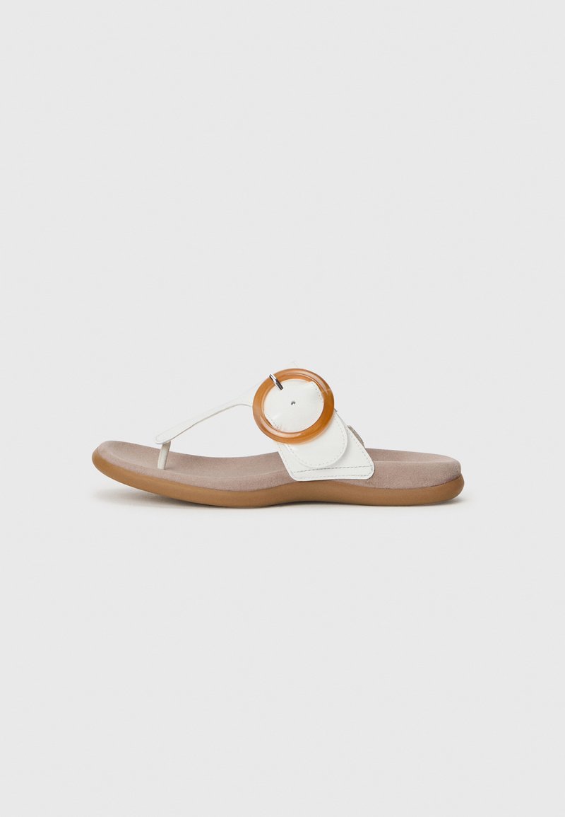 Witte teenslippers met een cirkelvormig beige decoratief element, tegen een effen witte achtergrond, met een gewatteerde voetbed.