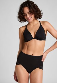 Zwarte driehoekige beha met verstelbare bandjes en een gladde textuur, gecombineerd met zwarte slip met hoge taille en kantaccenten.