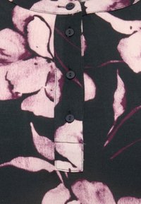 Mustast värvi tume topp heledate roosade lillemustritega, millel on nööpidega plastron ja ümar kaelus.