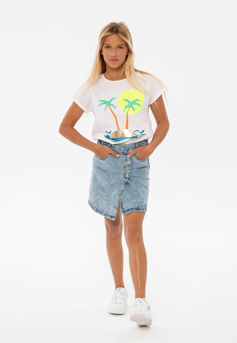 Camiseta blanca con un gráfico colorido de palmera y sol, combinada con una falda de mezclilla azul claro con botones en el frente y una abertura lateral.