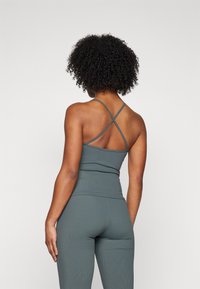 Green ribbed athletic top with crossed straps, fitted design, and a smooth texture, paired with matching high-waisted leggings.