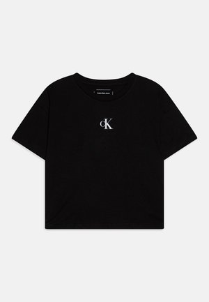 T-shirt preta cortada feita de algodão, com mangas curtas e um pequeno logo branco "ck" no peito. Textura suave e design simples.