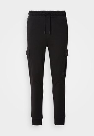 Black jogger pants made of soft fabric, featuring a drawstring waistband, side cargo pockets, and fitted cuffs. Smooth texture and simple design.