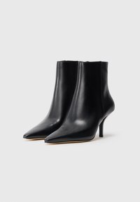 Black leather ankle boots with pointed toes, slim heels, and a sleek design. Smooth texture, minimal stitching, and no visible hardware.