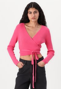 Rosa ribbestrikket genser med V-hals og lange ermer, med et knyte-detalj i livet og en kort design.