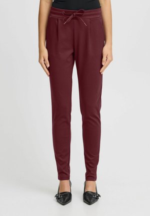 Burgundy tapered joggers made of soft fabric, featuring an elastic waistband with a drawstring and side pockets.