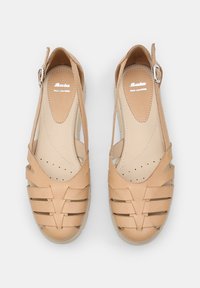 Sandalias de cuero beige con un diseño abierto que presenta correas entrelazadas, punta redondeada y una hebilla ajustable en la correa del tobillo.