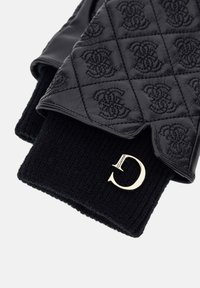 Black leather gloves with quilted pattern and embossed logos, paired with black knit cuffs featuring a gold metallic "C" brand tag.