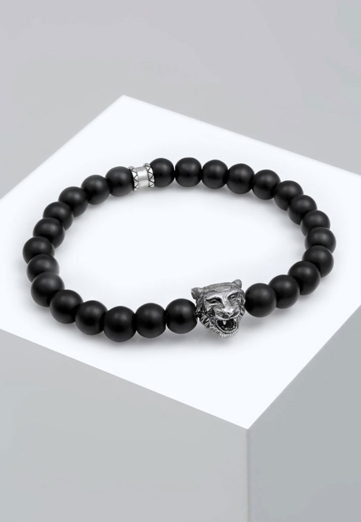 Bracciale in perline nere con perle di ossidiana opaca e charm a forma di testa di leone in tonalità argento, con dettagli facciali curati. Inclusi accenti geometrici sottili.