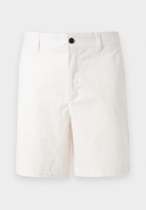 Shorts blancs jusqu'aux genoux avec passants pour ceinture et un bouton noir à la taille, présentés sur un fond clair uni.