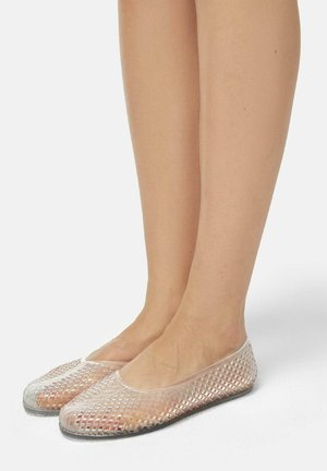 Transparent, flat shoes with a grid-like pattern. Flexible material, rounded toe, slim profile, and a solid black sole.