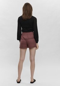 Czarna koszula z długim rękawem i bordowe spodenki w wzory z elastycznym pasem, ozdobione koronką i teksturowanym, wplecionym wzorem.