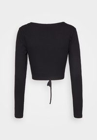 Top corto nero a costine con maniche lunghe e dettaglio con lacci sul retro. Presenta una scollatura ampia per una vestibilità comoda. Il tessuto appare texturizzato.