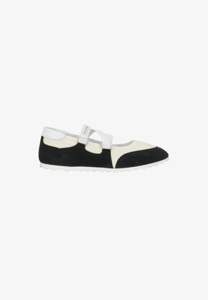 Scarpa bassa da donna con pannelli in camoscio nero e bianco e cinturino bianco regolabile sul collo del piede su suola bianca.