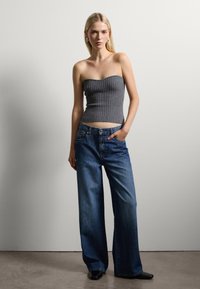 Top strapless de canalé gris combinado con jeans de denim azul de corte holgado. Los jeans presentan un diseño clásico de cinco bolsillos y una cintura de altura media.