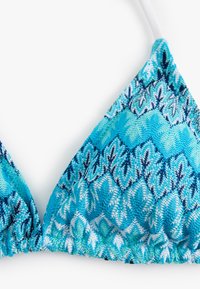 Top de bikini con patrón azul y turquesa, de forma triangular, con tejido texturizado y detalle fruncido a lo largo del borde inferior.