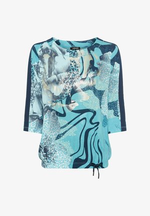 Haut bleu clair avec des motifs floraux et géométriques abstraits. Il présente des manches trois-quarts, un col rond et un ourlet à cordon de serrage.