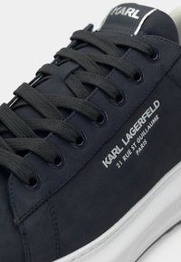 Navy plava kožna tenisica s tamnim vezicama i detaljima s logotipom. Ima glatku teksturu, perforirane akcente i bijeli gumeni potplat.