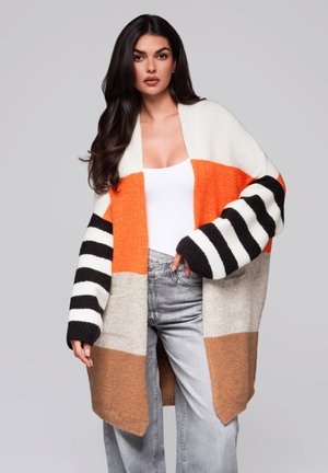Cardigan surdimensionné coloré présentant des rayures orange, gris, noir et blanc. Texture tricotée avec des manches longues et un design à l'avant ouvert.