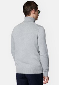 Jasnoszary sweter z golfem wykonany z dzianiny, z prążkowanymi mankietami i dołem, o luźnym kroju i minimalisticznym designie.