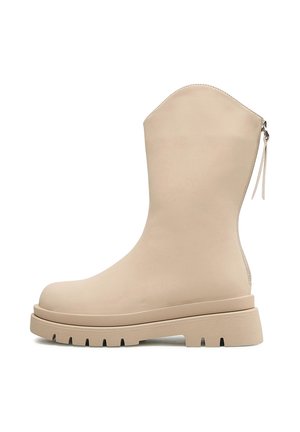 Beżowy skórzany but do połowy łydki z masywną podeszwą i tylnym suwakiem, z zaokrąglonym noskiem i bieżnikowaną podeszwą zapewniającą przyczepność.