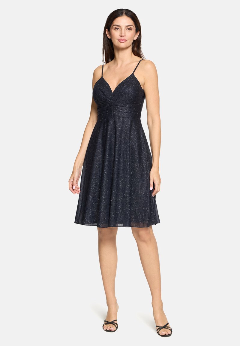 Robe bleu marine avec texture scintillante, corsage ajusté et jupe évasée, dotée de fines bretelles et d'un décolleté en V. Longueur mi-mollet.