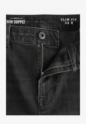 Melni denim bikses ar slaidu piegriezumu, ar metāla rāvējslēdzēju, pogu aizdari un piecu kabatu dizainu. Teksturēta auduma apdare ar maigu finišu.