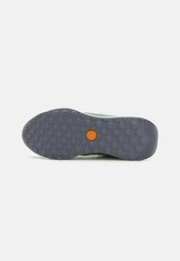 Grüner Wanderschuh mit einer strukturierten grauen Gummisohle, ausgestattet mit einem gemusterten Grip und einem orangefarbenen Logo in der unteren Mitte.