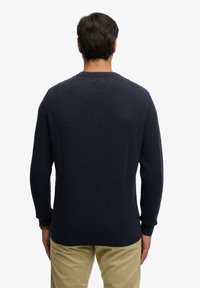 Marineblauwe trui met structuur, lange mouwen en een ronde hals. Voorzien van een geribbelde zoom en manchetten. Minimalistisch ontwerp, geschikt voor casual gebruik.