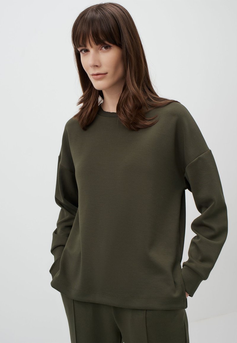 Felpa verde oliva con collo rotondo e maniche lunghe e rilassate. Texture liscia, vestibilità casual e dettaglio cucito vicino all'orlo.