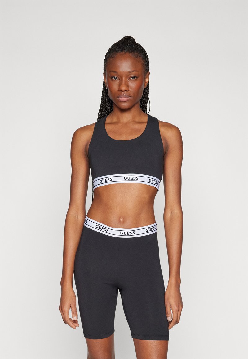 Top corto atlético negro y pantalones cortos de cintura alta con una banda elástica blanca con marca. Textura suave, diseño ajustado y sin patrones visibles.