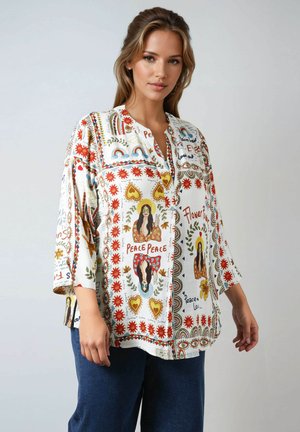 Blouse ample en tissu blanc avec des motifs floraux et abstraits colorés, ornée de détails décoratifs et d'un col décontracté.