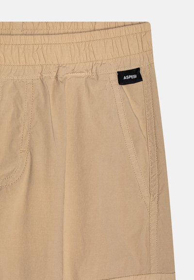 Beige lette shorts med elastisk linning, sidelommer og et sort merke som leser "ASPESI." Glatt tekstur og enkel design.
