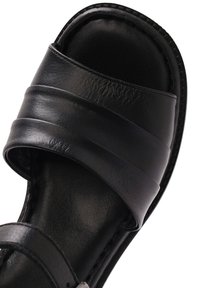 Black slide sandal featuring two horizontal straps made of smooth leather. The footbed is textured with a simple, flat design.